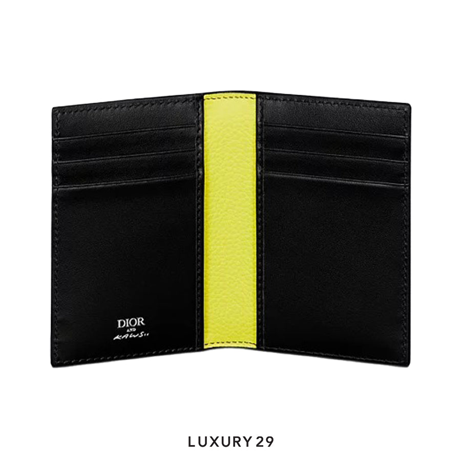 Black wallet with yellow interior section, featuring Dior branding, on a white background.