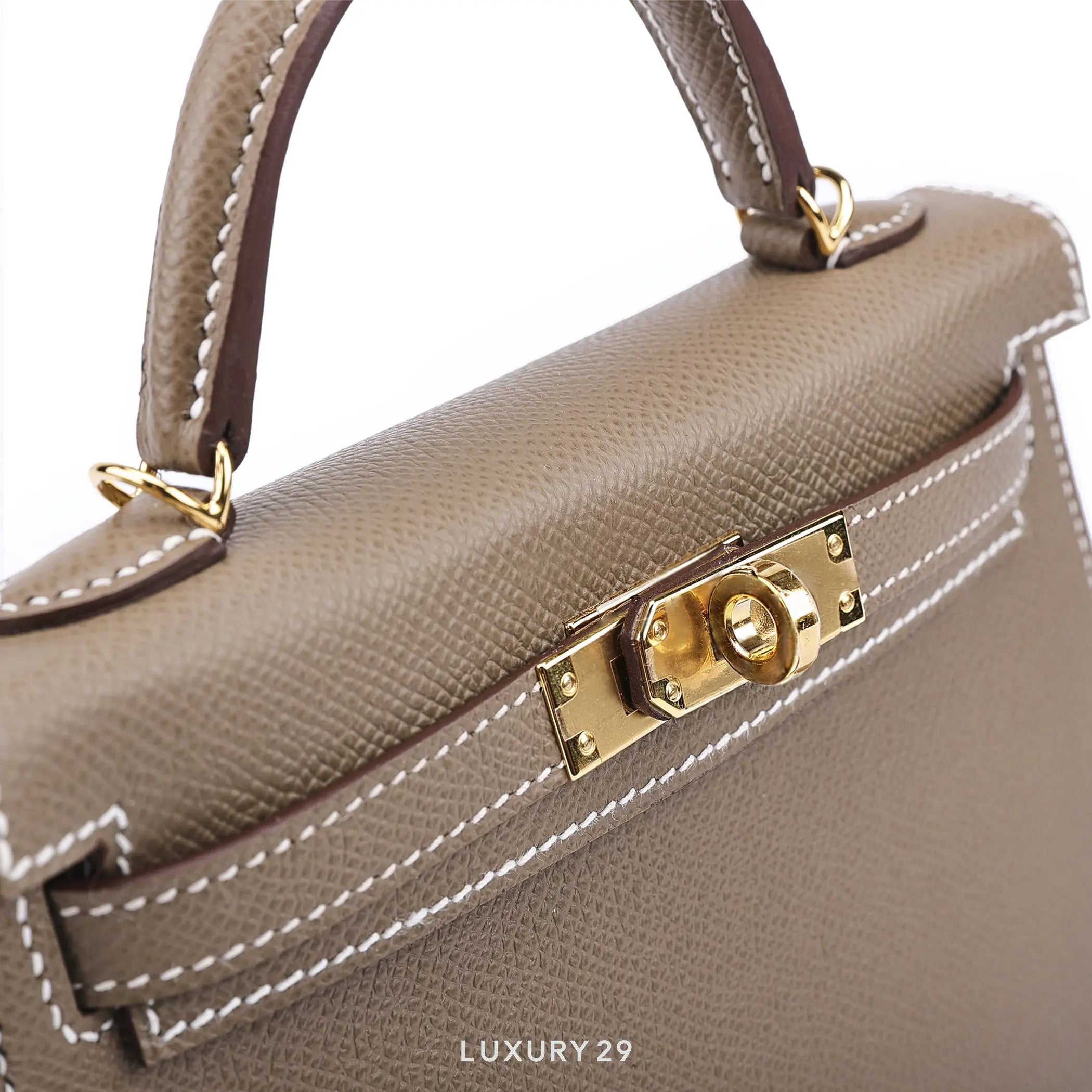 Close-up of a beige handbag with gold hardware on a white background