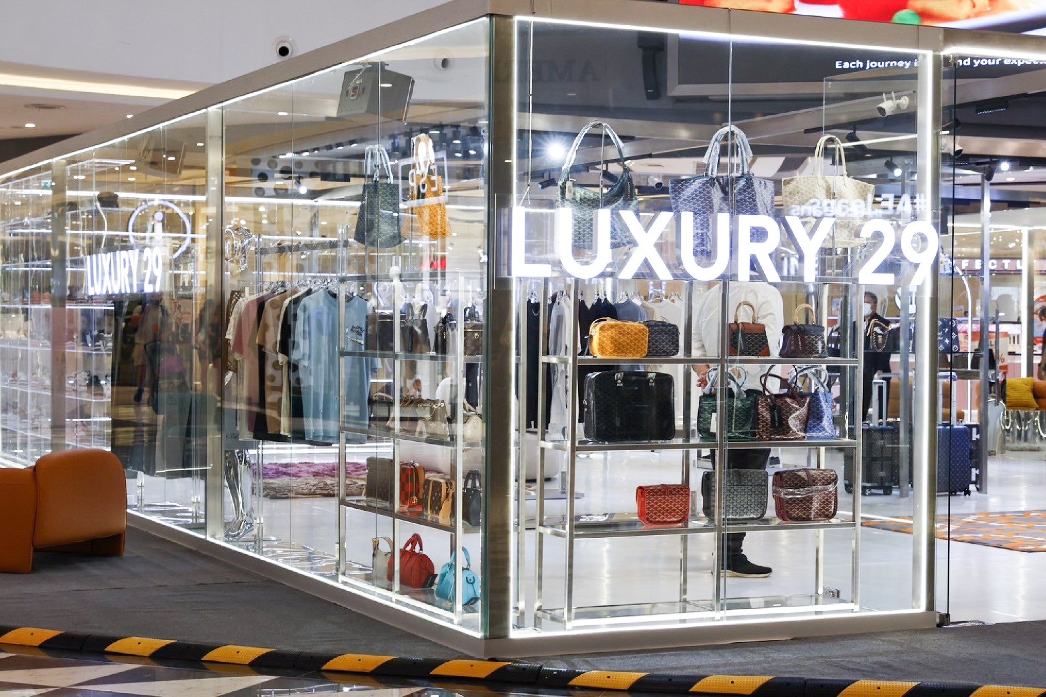 Luxury brand display case with handbags and clothing in a store setting.