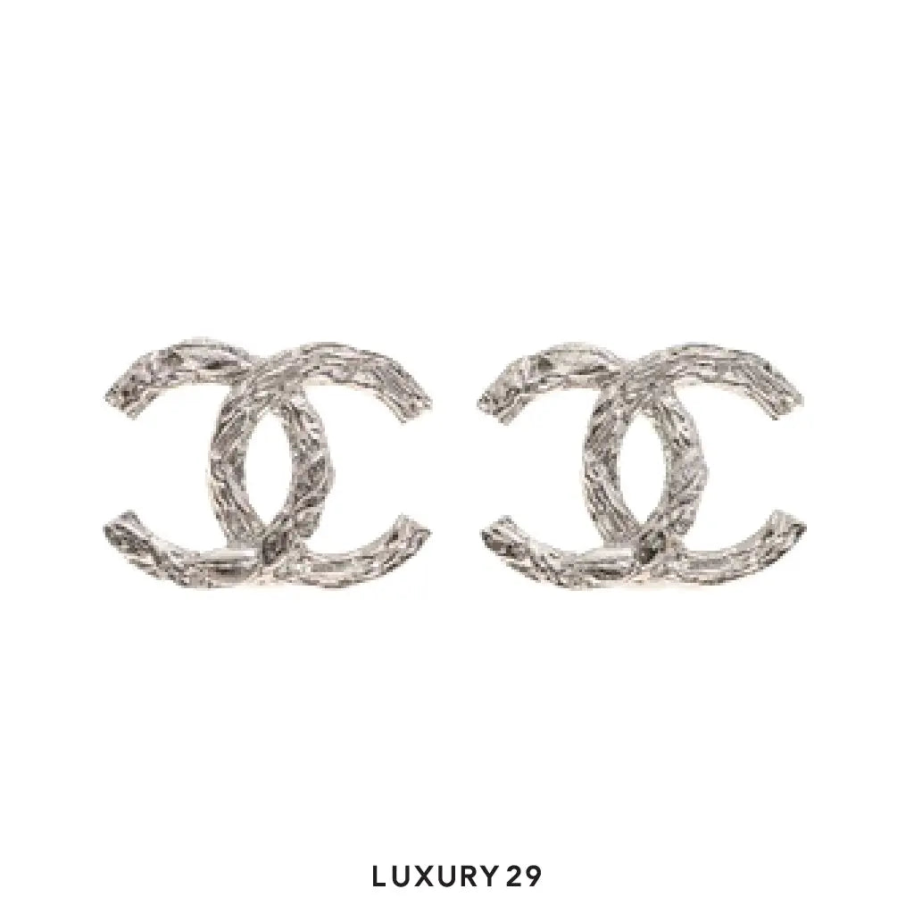 Pair of silver Chanel earrings on a white background with 'LUXURY 29' text.