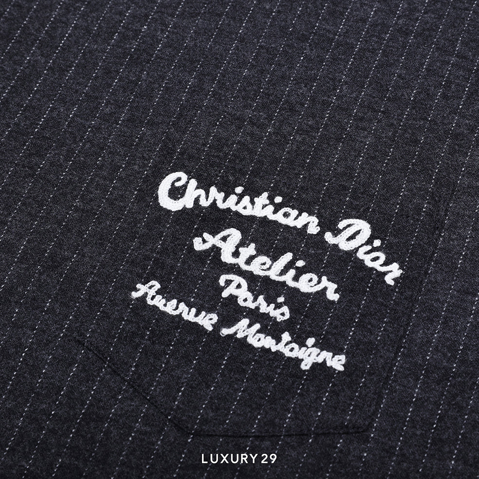 Embroidered text on a black pinstripe fabric with 'Christian Dior Atelier' branding.