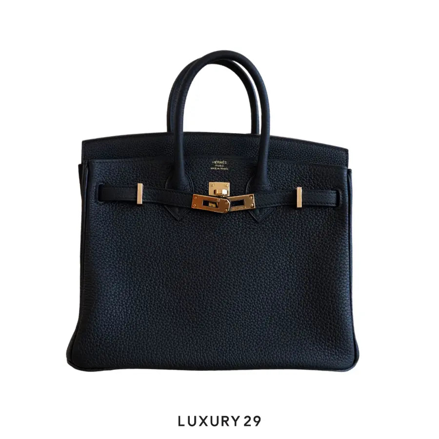 Black leather handbag with gold hardware on a white background