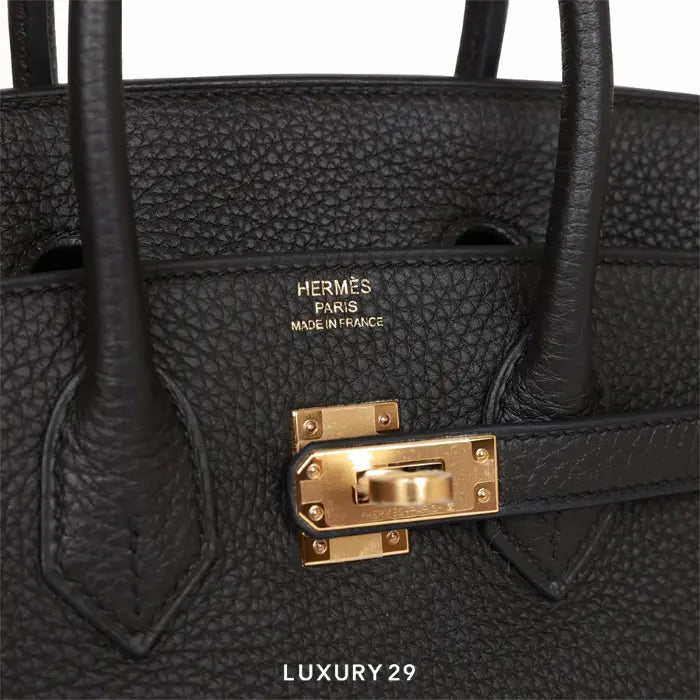 Black Hermès bag with gold hardware on a white background