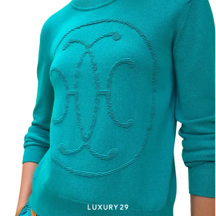 Teal sweater with embroidered design on a white background