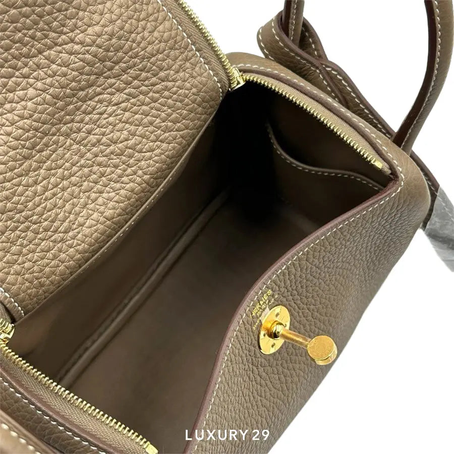 Brown leather handbag with gold zipper and clasp on a white background