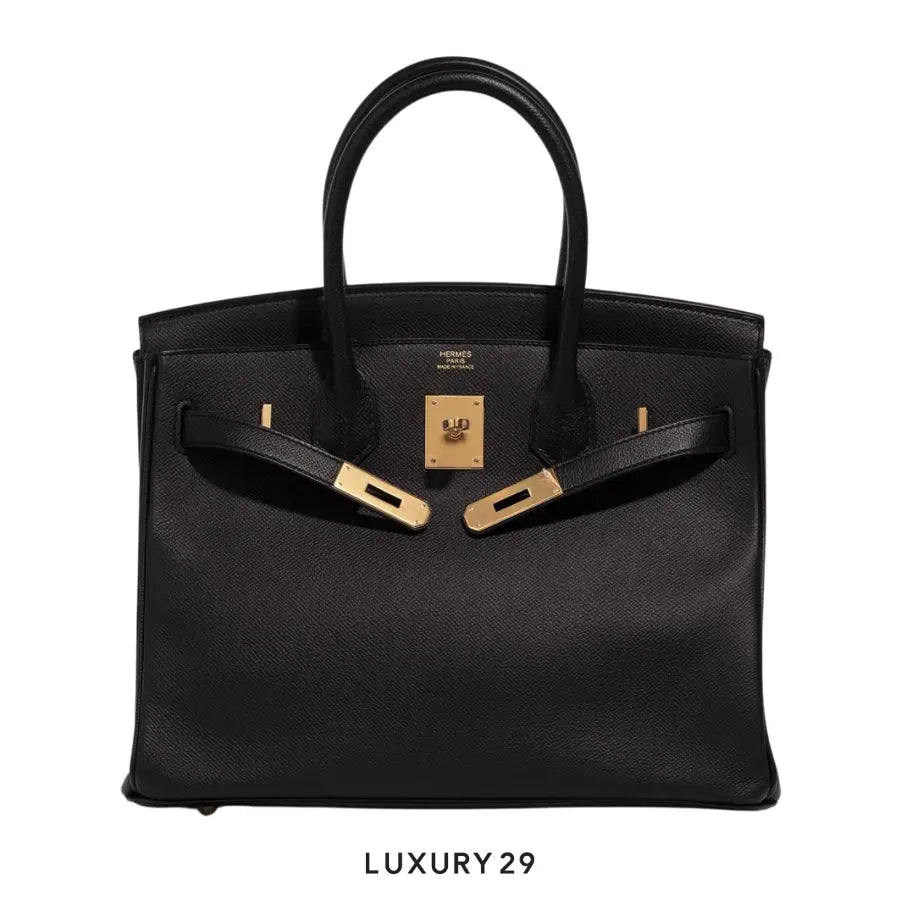 Black handbag with gold hardware on a white background