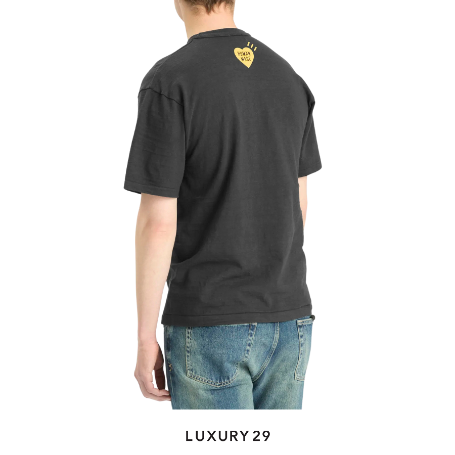 Person wearing a black t-shirt with a yellow heart logo on the back, standing against a white background.