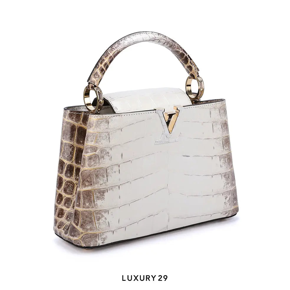 Luxury handbag with crocodile pattern and gold accents on a white background
