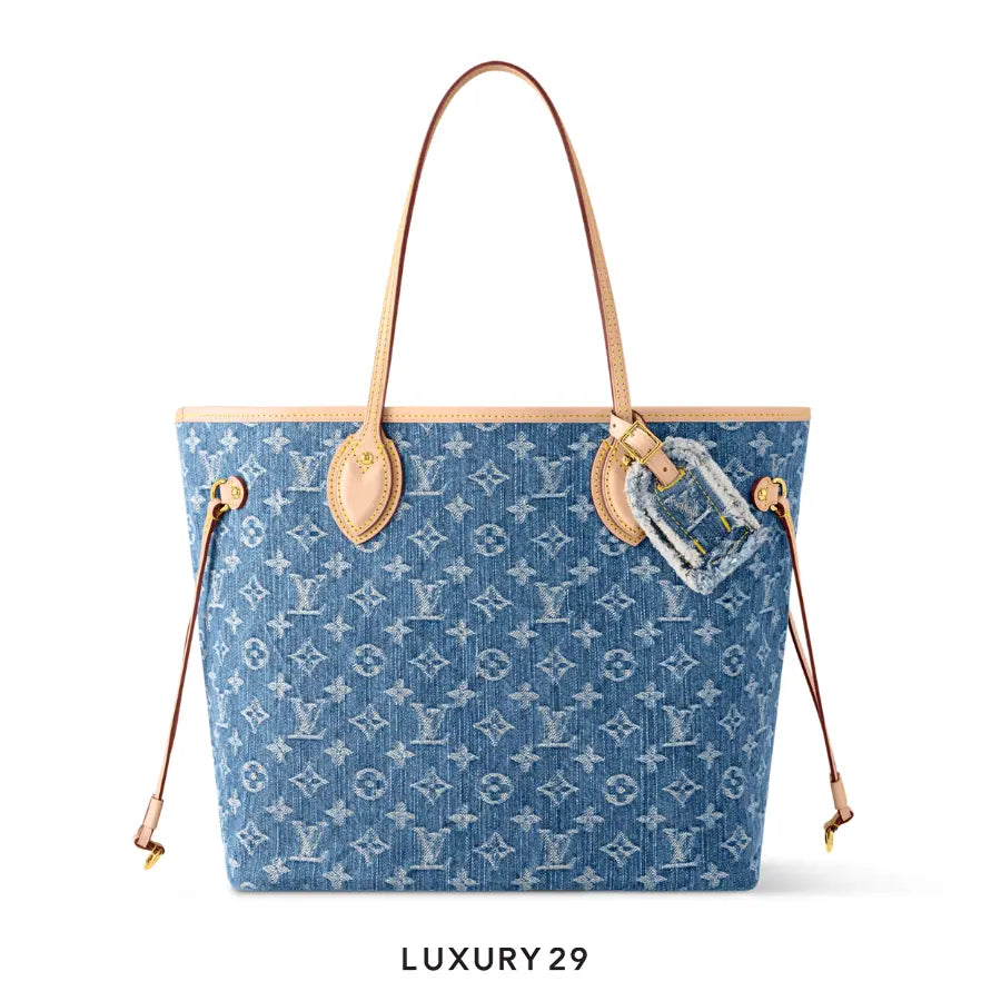 Blue denim handbag with tan leather straps and hardware on a white background