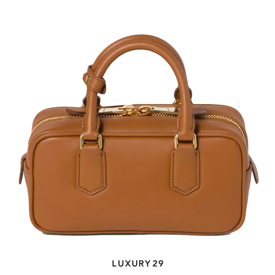 Brown leather handbag with gold zippers on a white background