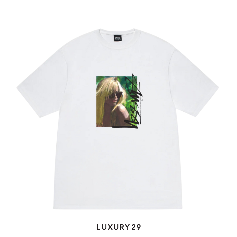 White t-shirt with a graphic design of a person with blonde hair and sunglasses, on a white background.